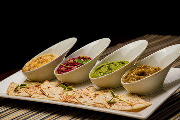 Colorful hummus bowls, healthy vegan dips. Traditional Middle eastern hummus, green hummus, beetroot hummus, spread. Assorted meze and dips with pita bread. Meze and snacks set, copy space.