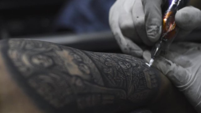 Tattoo artist holding a tattoo machine tattooing a person