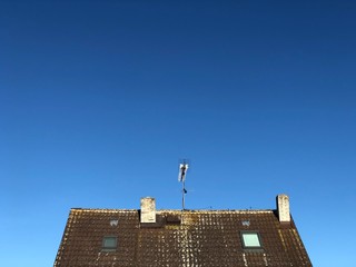 Old house roof with chimneys, windows and antenna.