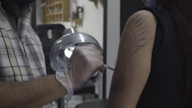 Tattoo artist holding a tattoo machine tattooing a person