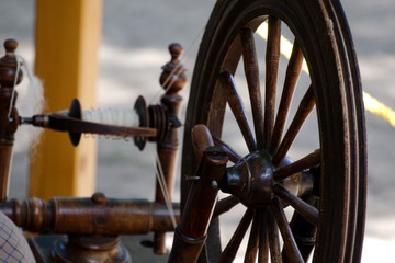 Old lady spinning yarn on spinning-wheel