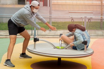 Fototapeta premium young man spinning his sister on the swing and enjoying Covid19 time with a mask