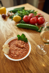 Close up of bowl of tomato soup or Pappa al Pomodoro served with a glass of white wine. The soup with tomatoes and bread, traditional Italian Tuscan dish