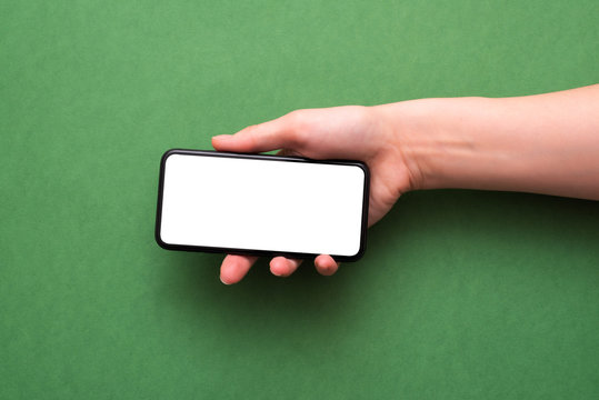 Blank Screen Mobile Phone In The Hand On The Green Background.