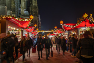 Night atmosphere of Weihnachtsmarkt, Christmas Market, with crowd of people and various beautiful decorated illuminate stalls beside Cologne Cathedral in Köln, Germany.