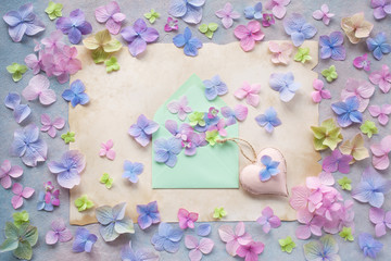 Obraz na płótnie Canvas Decorative background postcard with colored hydrangea flowers, paper, envelope and decor heart.