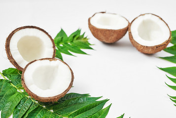 Flat lay coconut with half and leaves on white background. Hello summer! Green and white color. Copy space. Tropical nut coconut. Vegetarian, vegan, raw food, tropical fruits. Healthy food and diet