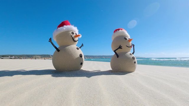 Two Sandy Christmas Snowmen are celebrating Christmas on a beautiful beach, zoom out