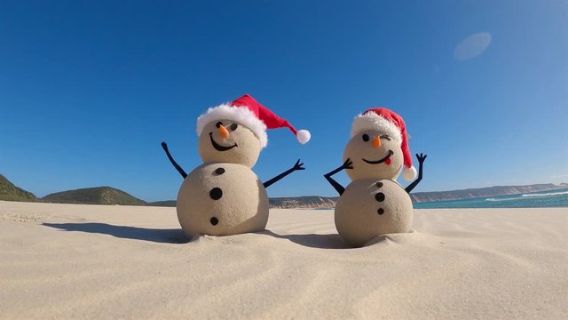 Two Sandy Christmas Snowmen are celebrating Christmas on a beautiful beach, zoom in