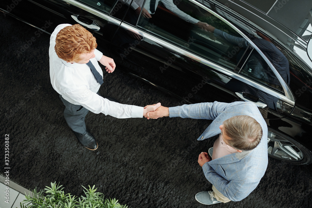 Poster top view of young sales manager in formalawear shaking hand of client