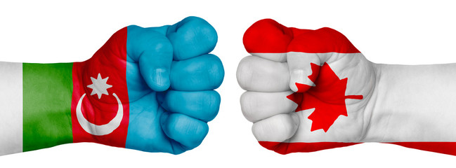 Two hands are clenched into fists and are located opposite each other. Hands painted in the colors of the flags of the countries. Canada vs Azerbaijan