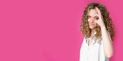 Portrait of a beautiful young woman makes a ok gesture, demonstrates agreement, loves an idea, smiles happily, models indoors. Well thank you.