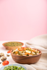 Mung bean porridge with quail eggs, tomatoes and microgreen sprouts on a white and pink background. Side view, selective focus, copy space.