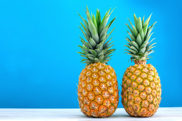 two fresh ripe pineapples on blue background