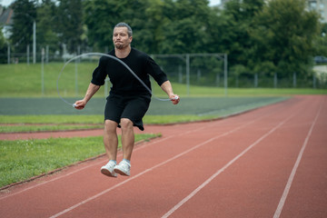 Obraz premium young athlete has workout and jumps on skipping rope outdoor