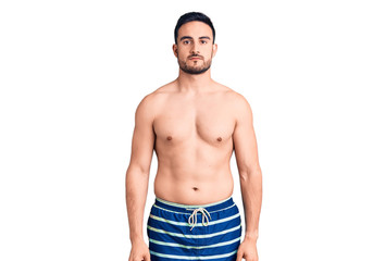 Young handsome man wearing swimwear relaxed with serious expression on face. simple and natural looking at the camera.
