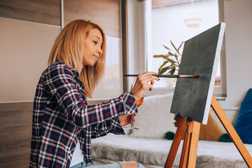 Beautiful artist woman painting in her room.