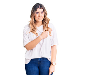 Young caucasian woman wearing casual clothes pointing aside worried and nervous with forefinger, concerned and surprised expression