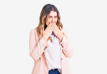 Young caucasian woman wearing business clothes laughing and embarrassed giggle covering mouth with...