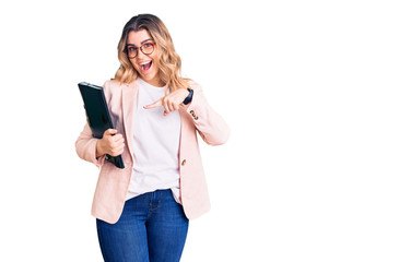 Young caucasian woman wearing business clothes and glasses holding binder smiling happy pointing with hand and finger