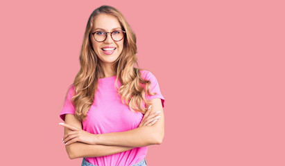 Young beautiful caucasian woman with blond hair wearing casual clothes and glasses happy face smiling with crossed arms looking at the camera. positive person.