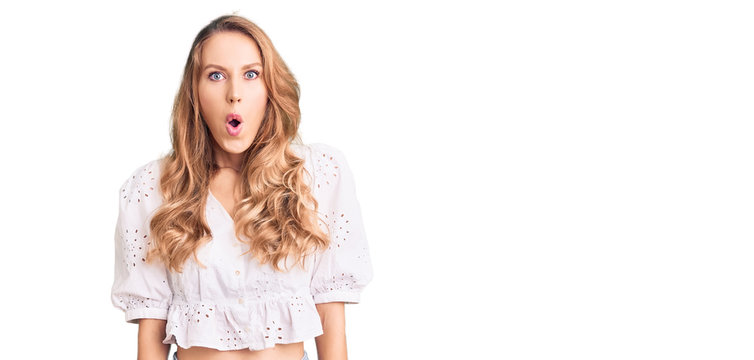 Young caucasian woman with blond hair wearing elegant summer tshirt scared and amazed with open mouth for surprise, disbelief face