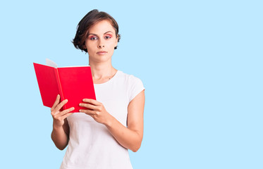 Beautiful young woman with short hair reading a book thinking attitude and sober expression looking self confident