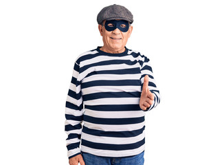 Senior handsome man wearing burglar mask and t-shirt smiling cheerful offering palm hand giving assistance and acceptance.