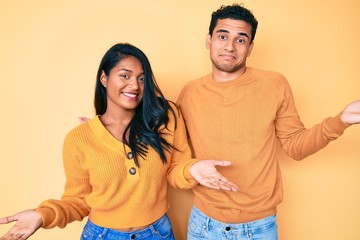 Beautiful latin young couple wearing casual clothes together smiling showing both hands open palms, presenting and advertising comparison and balance