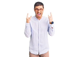 Handsome young man with bear wearing elegant business shirt and glasses shouting with crazy expression doing rock symbol with hands up. music star. heavy music concept.