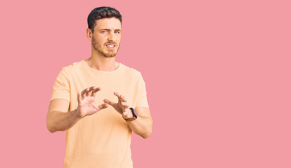 Handsome young man with bear wearing casual yellow tshirt disgusted expression, displeased and...