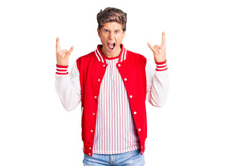 Young handsome man wearing baseball uniform shouting with crazy expression doing rock symbol with hands up. music star. heavy music concept.