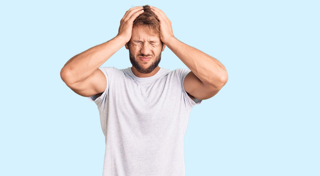 Young caucasian man wearing casual white tshirt suffering from headache desperate and stressed because pain and migraine. hands on head.