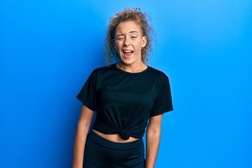 Beautiful caucasian teenager girl wearing black sportswear winking looking at the camera with sexy...