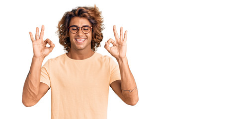 Young hispanic man wearing casual clothes and glasses relax and smiling with eyes closed doing meditation gesture with fingers. yoga concept.