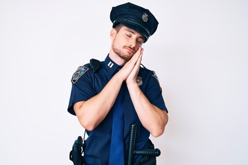 Young caucasian man wearing police uniform sleeping tired dreaming and posing with hands together while smiling with closed eyes.