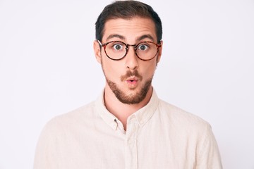 Obraz premium Young handsome man wearing casual clothes and glasses scared and amazed with open mouth for surprise, disbelief face