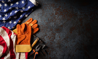 Happy Labor day concept. American flag with different construction tools on dark stone background,...