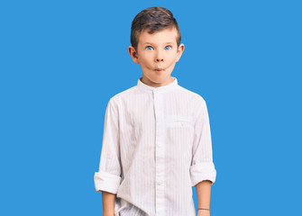 Cute blond kid wearing elegant shirt making fish face with lips, crazy and comical gesture. funny expression.