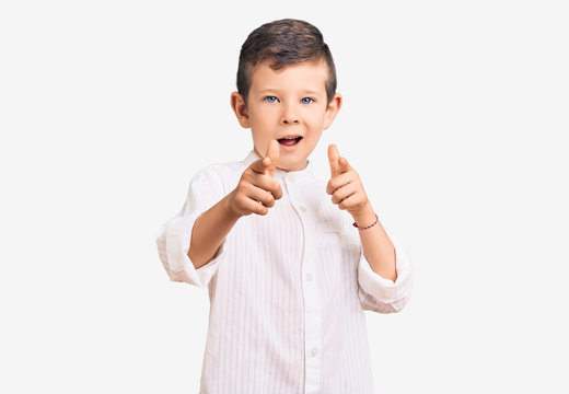 Cute blond kid wearing elegant shirt pointing fingers to camera with happy and funny face. good energy and vibes.