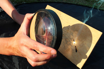 Sunlight burns wood, having passed through the magnifying glass