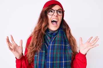 Young beautiful woman wearing casual winter scarf and glasses crazy and mad shouting and yelling...