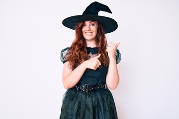Young beautiful woman wearing witch halloween costume pointing to the back behind with hand and thumbs up, smiling confident