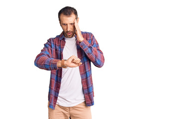 Young handsome man wearing casual clothes looking at the watch time worried, afraid of getting late