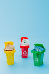 Yellow, green and red recycle bins with recycle symbol on blue background. Keep city tidy, Leaves the recycling symbol. Nature protection concept
