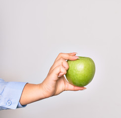 Hand of caucasian young woman holding green apple fruit over isolated white background