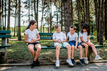 School boy with diabetes testing his blood sugar after physical education, friends support him.