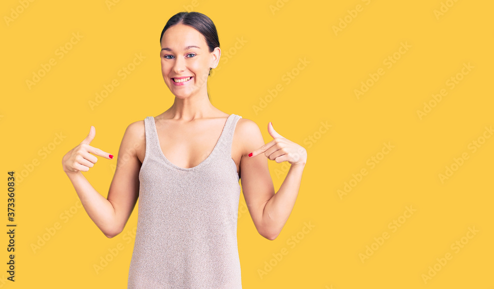 Wall mural beautiful brunette young woman wearing casual dress looking confident with smile on face, pointing o