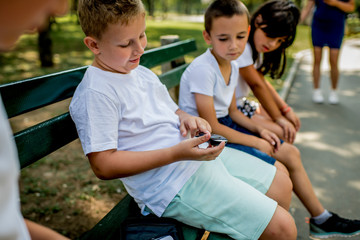School boy with diabetes testing his blood sugar after physical education, friends support him.