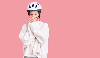 Beautiful brunette young woman wearing bike helmet and sporty clothes shocked covering mouth with hands for mistake. secret concept.